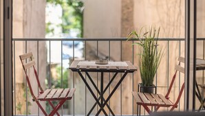 A balcony with a small table, two wooden chairs, and a potted plant. - Elegant Mavili Suite by Cloudkeys (Athens)