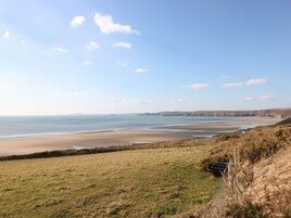 Un paisaje costero con playa, campos de hierba y una valla.