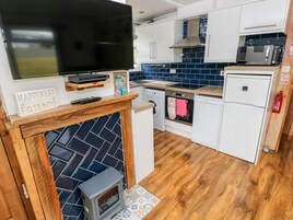 Una cocina compacta con estufa integrada, microondas, lavavajillas y un televisor sobre la chimenea.
