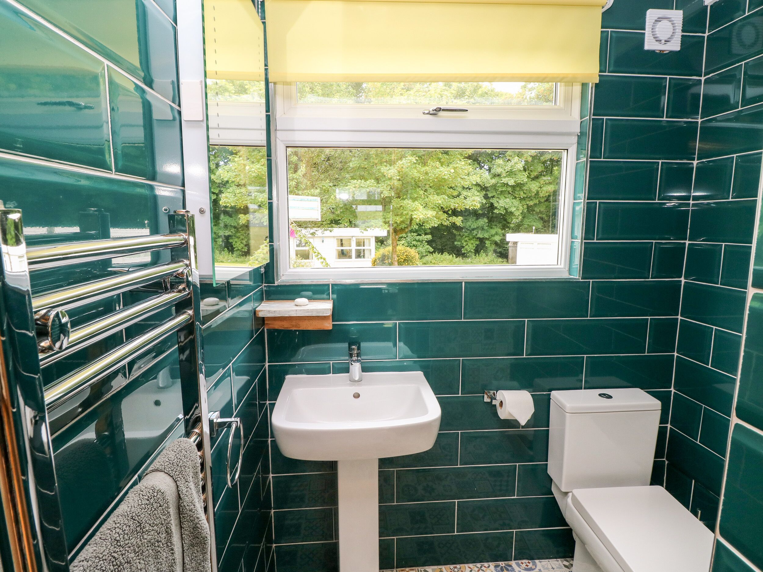 A bathroom with a sink, toilet, and a window with a view of trees.