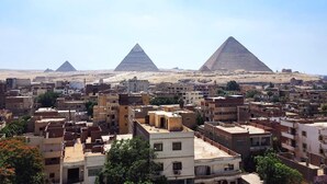 Paesaggio urbano con diverse piramidi sullo sfondo e una zona densamente edificata in primo piano.