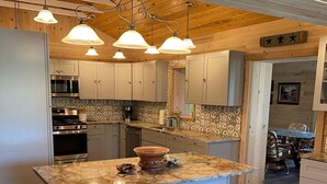 Eine moderne Küche mit einer großen Kochinsel, Edelstahlgeräten und Holzbalken an der Decke.