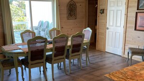 Ein Essbereich mit Holztisch und Stühlen, einer Kristallleuchter und Blick durch eine Glastür.