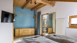 Une chambre avec un lit, des meubles en bois, une télévision et une fenêtre.