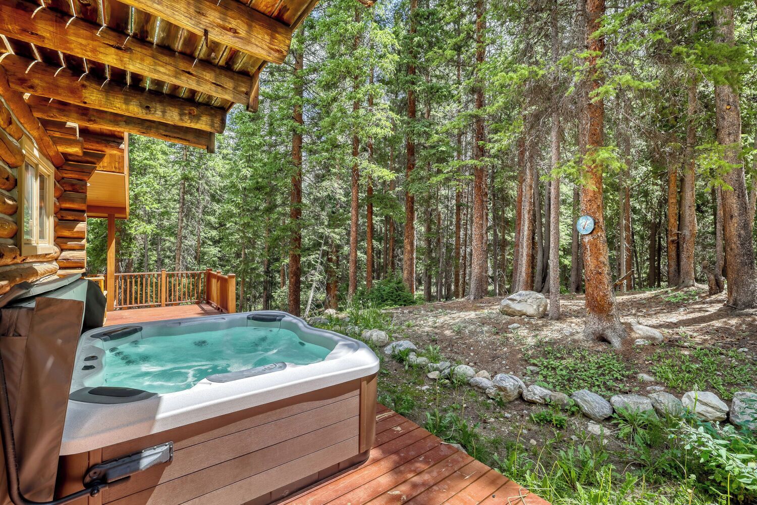 Een hottub op een houten terras, met een bos op de achtergrond.