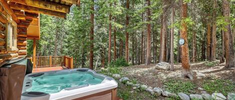 Een hottub op een houten terras, met een bos op de achtergrond.