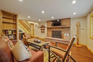 A living room with a fireplace, a bookshelf, a leather sofa, and a staircase.