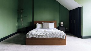 A bedroom with a wooden bed, a bedside table, a floor lamp, and a wardrobe. - Emerald 2BD Retreat in Historic Building, New Town (Edinburgh)