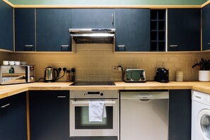 A compact kitchen with a built-in oven, a dishwasher, a toaster, and a kettle. - Emerald 2BD Retreat in Historic Building, New Town (Edinburgh)