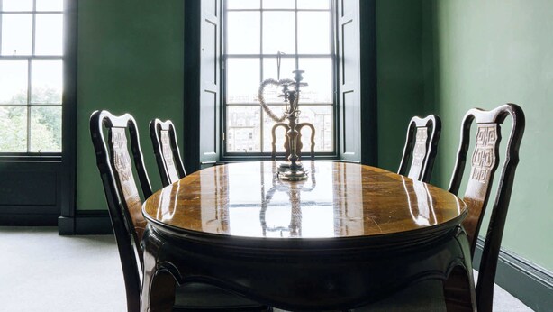 A round wooden table with ornate chairs, a hookah, and a view through large windows. - Emerald 2BD Retreat in Historic Building, New Town (Edinburgh)