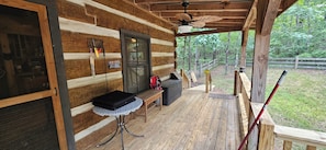 A wooden cabin with a porch, a ceiling fan, a bench, and a table with a black case. - THE WOODLANDS - VERY QUIET SECLUDED CABIN (Mentone)