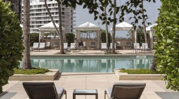 A poolside area with lounge chairs, a swimming pool, and a view of high-rise buildings. - Four Seasons Studio - Privately Owned Unit (Miami)