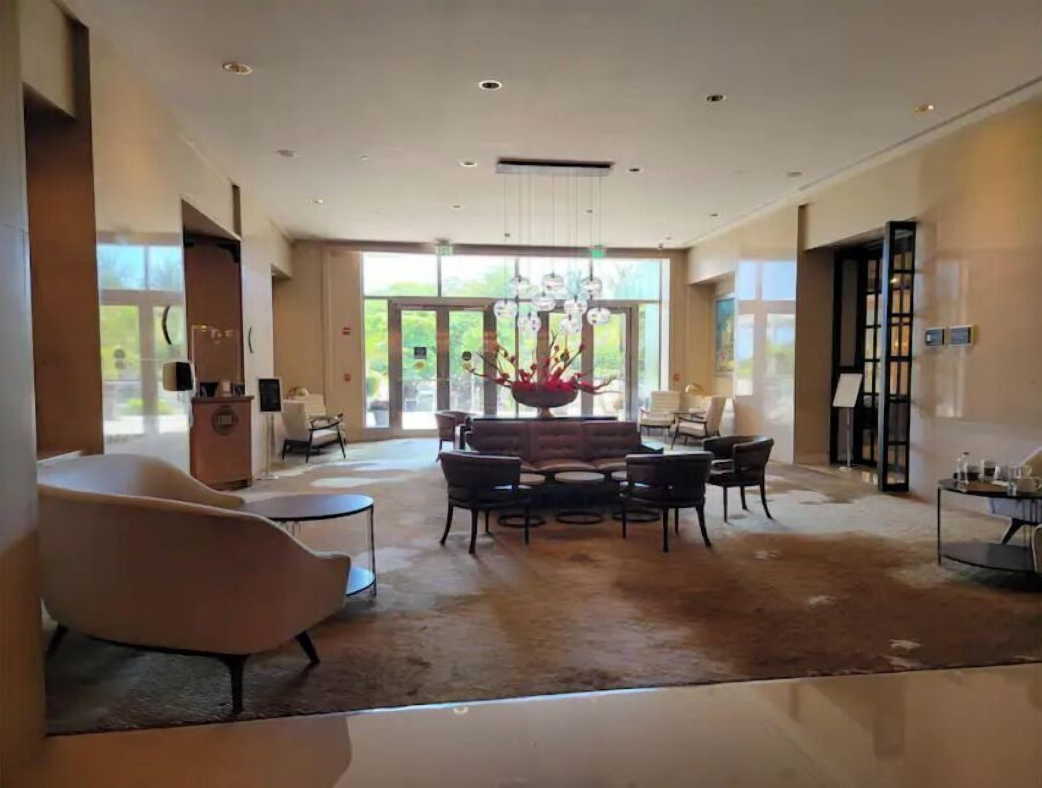 A spacious lobby with a central seating area, large windows, and a chandelier.