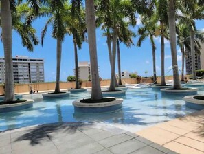 A pool area with palm trees and a clear blue sky. - Four Seasons Studio - Privately Owned Unit (Miami)