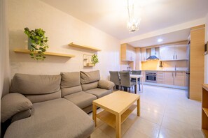 Un salon moderne avec un canapé beige, une table basse en bois et un coin repas comprenant des chaises et une table.