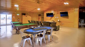 A wooden interior with a pool table, chairs, and a billiards rack. - Ellipse Global Lodge (Carlsbad)
