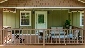 A covered porch with a railing, a door, and a seating area with chairs.
