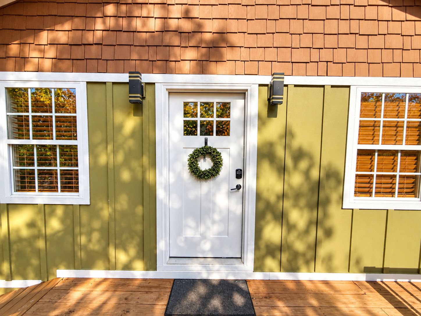 A house with a white front door, a wreath, and two windows with blinds.