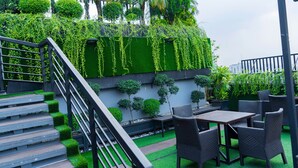 A rooftop terrace with a staircase, outdoor seating, and lush greenery. - Central Inn (Dhaka)