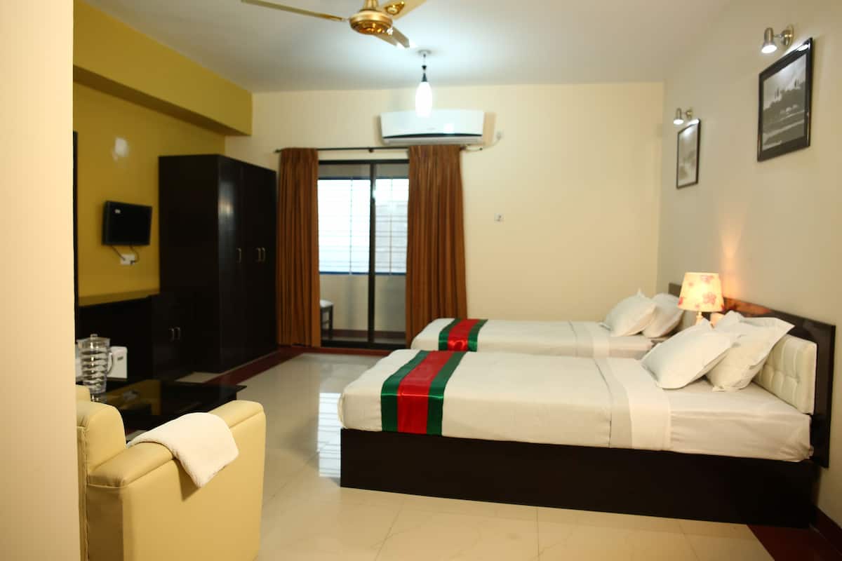 A hotel room with two beds, a TV, a ceiling fan, and an air conditioning unit.