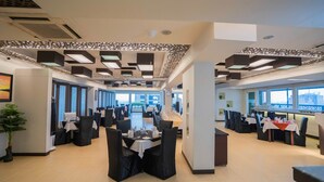 A modern restaurant with high ceilings, geometric light fixtures, and a long dining area with tables and chairs. - Central Inn (Dhaka)