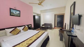 A hotel room with a bed, a desk, a television, a wardrobe, and a door.