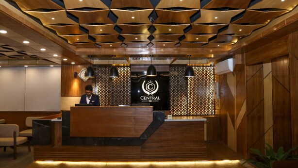 A hotel reception area with a modern design, featuring a wooden reception desk, a digital display with the hotel logo, and a patterned ceiling. - Central Inn (Dhaka)