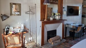 Una habitación acogedora con chimenea, un espejo, un televisor y una zona de comedor con mesa y sillas.