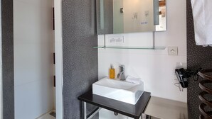 Un baño moderno con ducha, lavamanos y espejo.