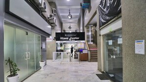 A hallway with a reception desk, a clock, and a sign for the Miami Center. - Rio Spot C058 (Rio de Janeiro)