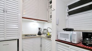 A compact kitchen with white cabinetry, a microwave, a coffee maker, and a blender. - Rio Spot C058 (Rio de Janeiro)