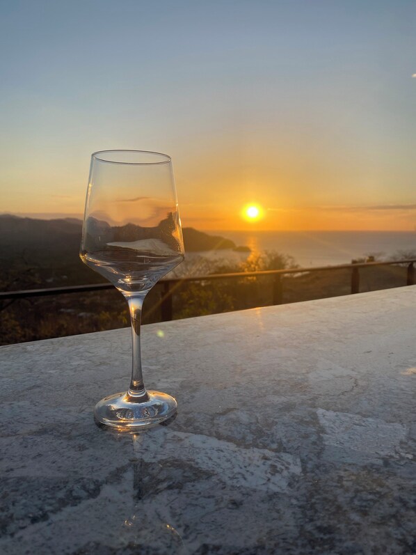 A glass of water on a marble surface with a sunset view in the background.