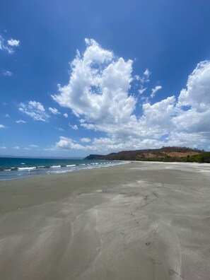 A beach with a clear sky and distant hills.