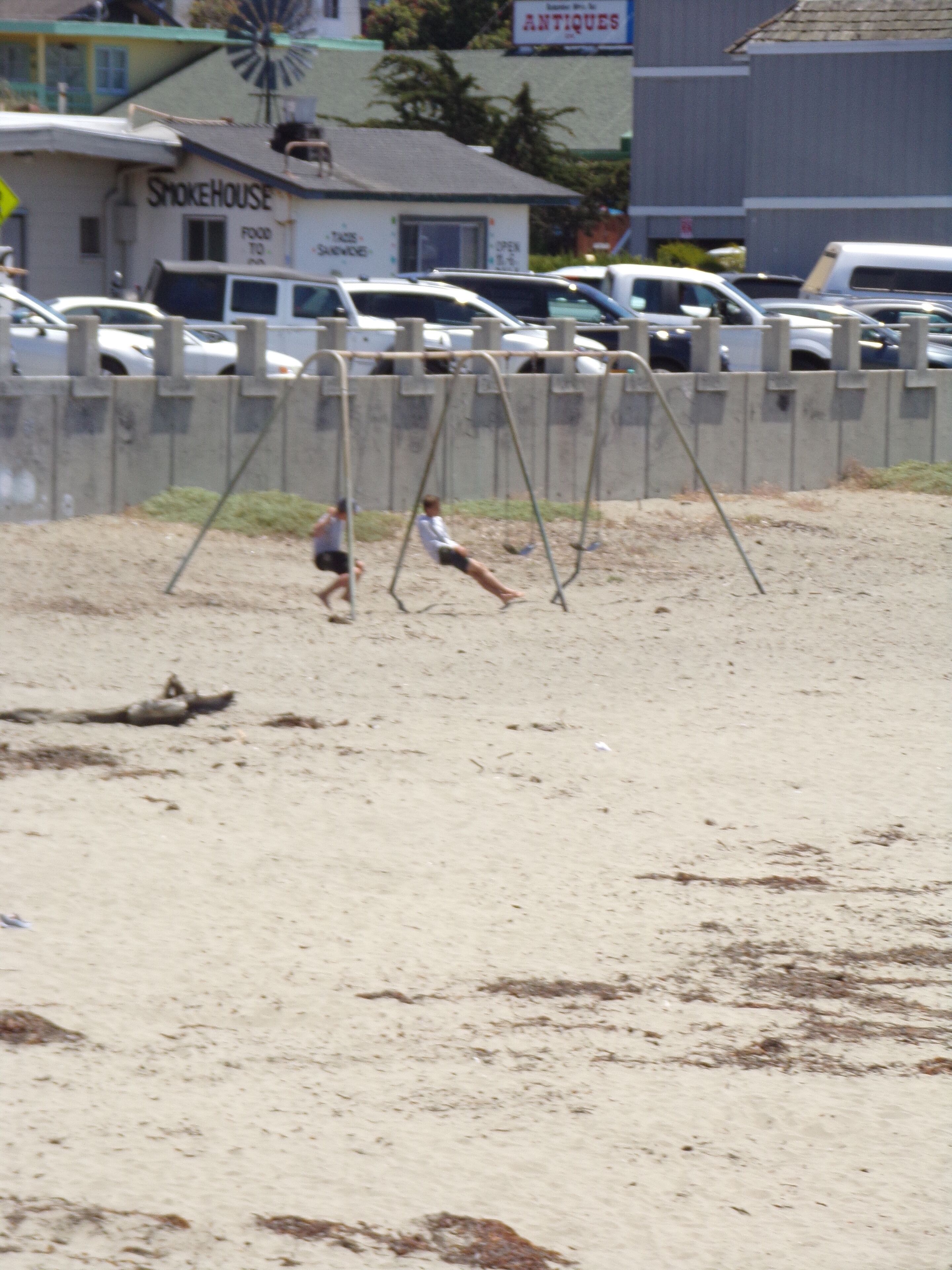 A sandy beach with swings and a fence.