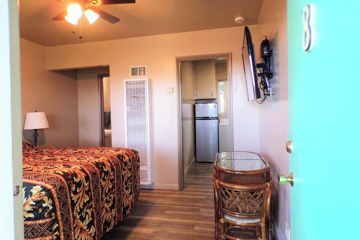 A bedroom with a bed, a ceiling fan, a nightstand, and a lamp.