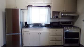 Una cocina compacta equipada con refrigerador, estufa, microondas y armarios.