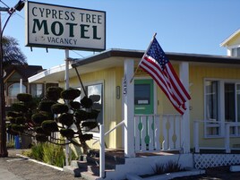 Un motel con un letrero que indica habitaciones disponibles, una bandera estadounidense y una puerta verde.