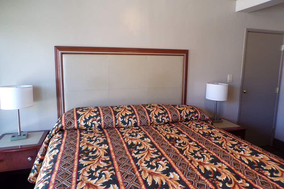 A hotel room with a bed, two bedside tables, and a door.