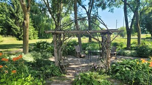 En have med en stensti, der fører til en træpergola med bænke.