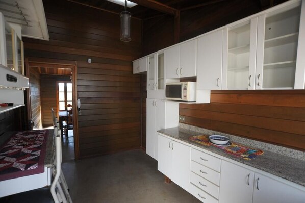 A compact kitchen with white cabinets, a microwave, and a granite countertop.