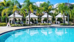 A swimming pool with lounge chairs and umbrellas, surrounded by palm trees. - 8 Bdrm Villa w/Pool, Theater Near Disney w/ Waterpark & Free Shuttle Service (Kissimmee)