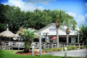 A restaurant with a sign reading "Cracker's" surrounded by palm trees and a thatched-roof structure.