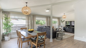 A modern living room with a sofa, TV, dining table, and chairs.