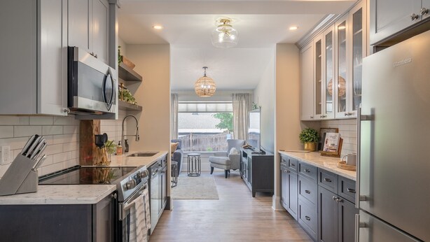 A modern kitchen with stainless steel appliances, a central island, and a view to a balcony.