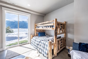 A bunk bed with a view of a snowy landscape through a large sliding door.