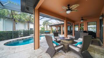 Une terrasse extérieure avec une piscine, des meubles en osier et des ventilateurs de plafond.