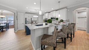 A modern kitchen with a central island, bar stools, and pendant lighting. - Beautiful Gulf Access home Amazing pool sunsets  (Punta Gorda)