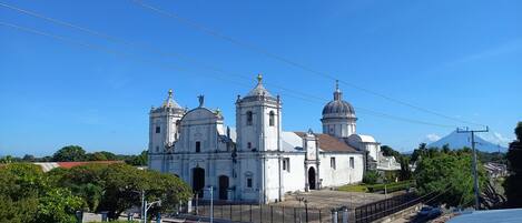 Une grande église blanche, dotée de plusieurs coupoles et de tours, entourée de verdure et surplombée d’un ciel bleu azur.