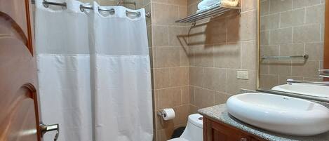 Un baño con ducha, inodoro y lavabo.