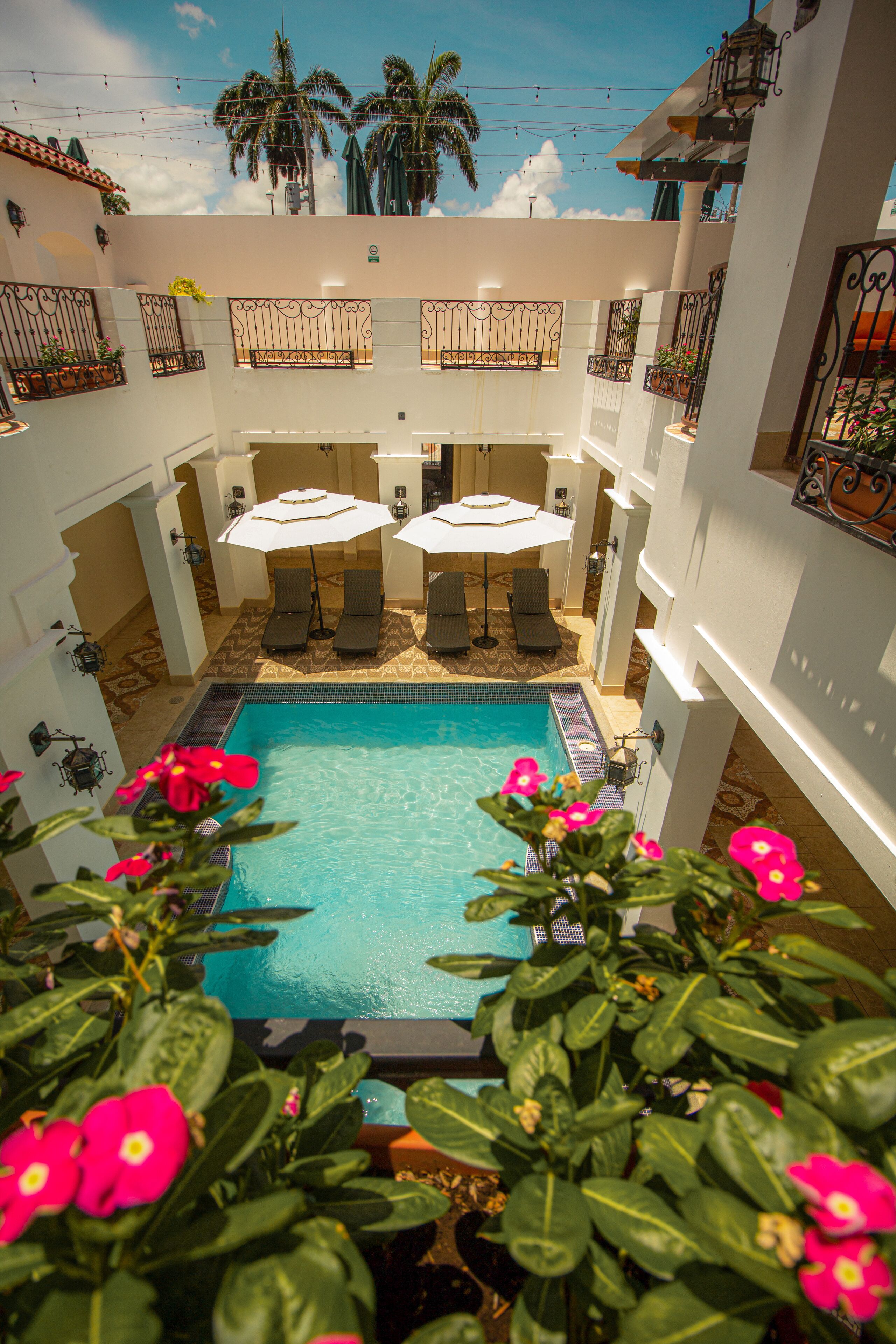 A pool area with a tiled floor, surrounded by white walls and balconies with railings.